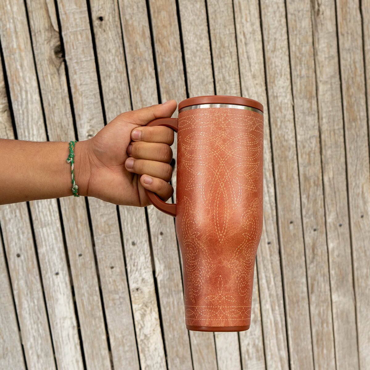 Hand holding brown saddle stitch swig life to go 40oz tumbler